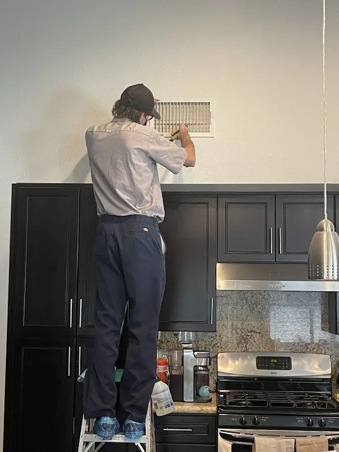 Technician inspecting an air vent during HVAC service in Camden
